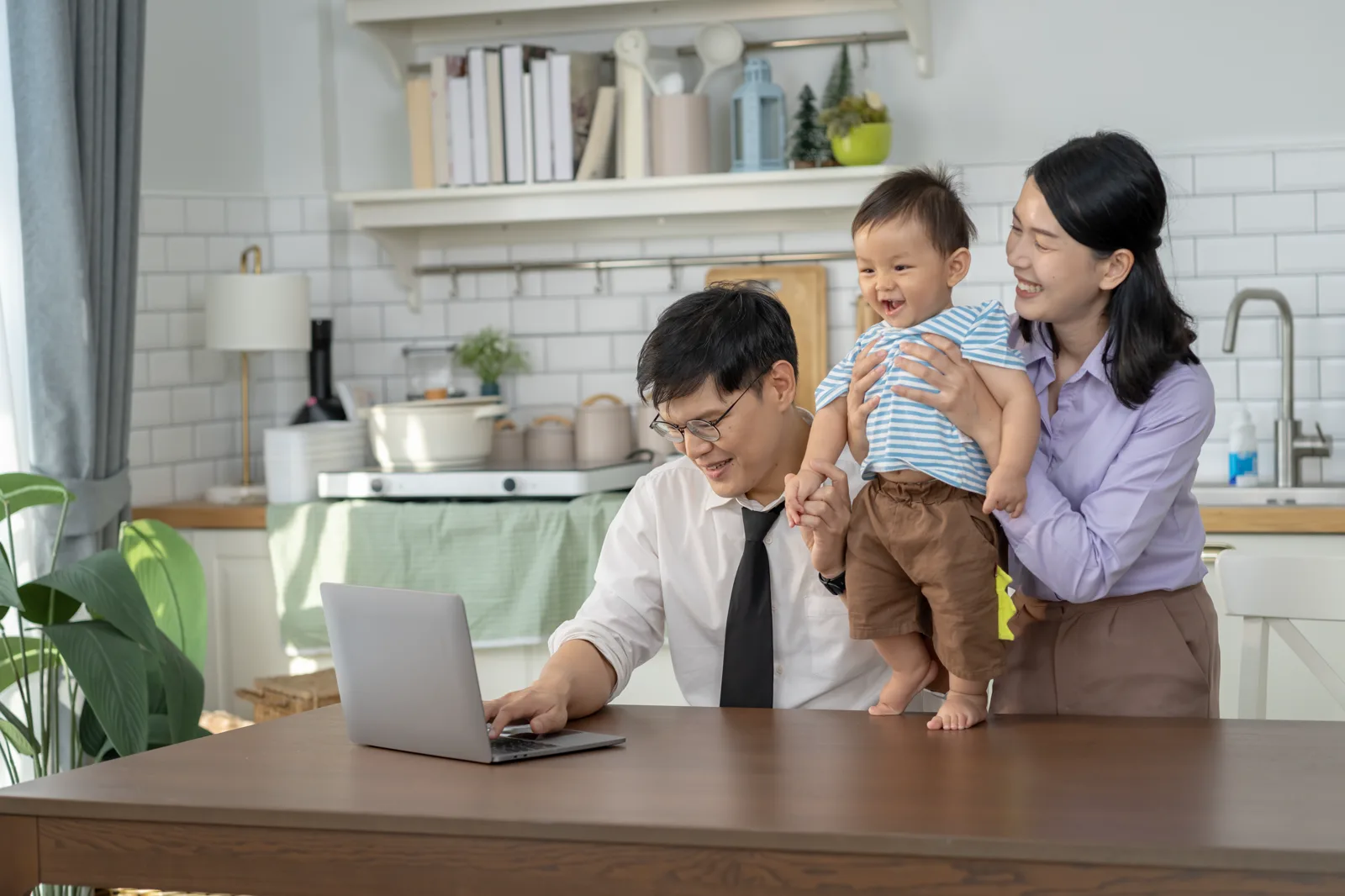 Two parents review health plan documents at home while caring for their baby