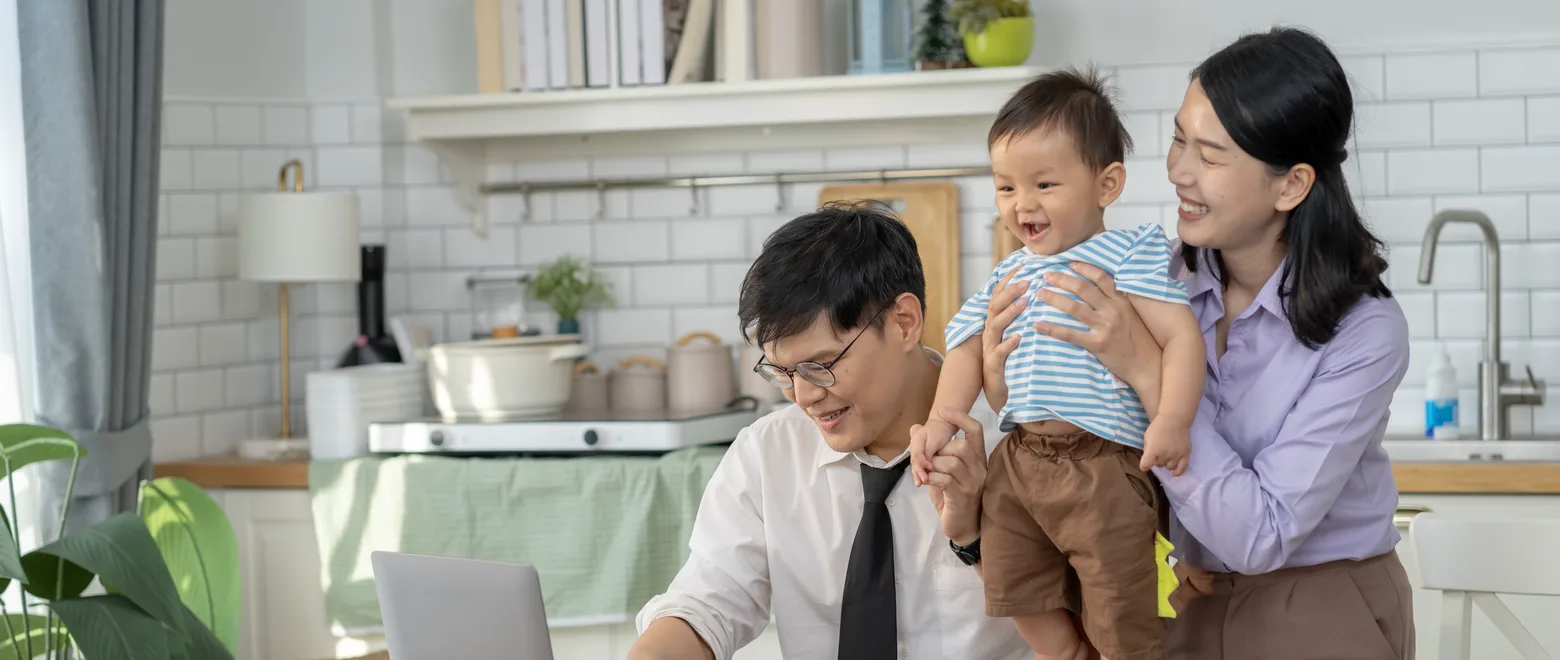 A family at a kitchen table with a laptop and paperwork