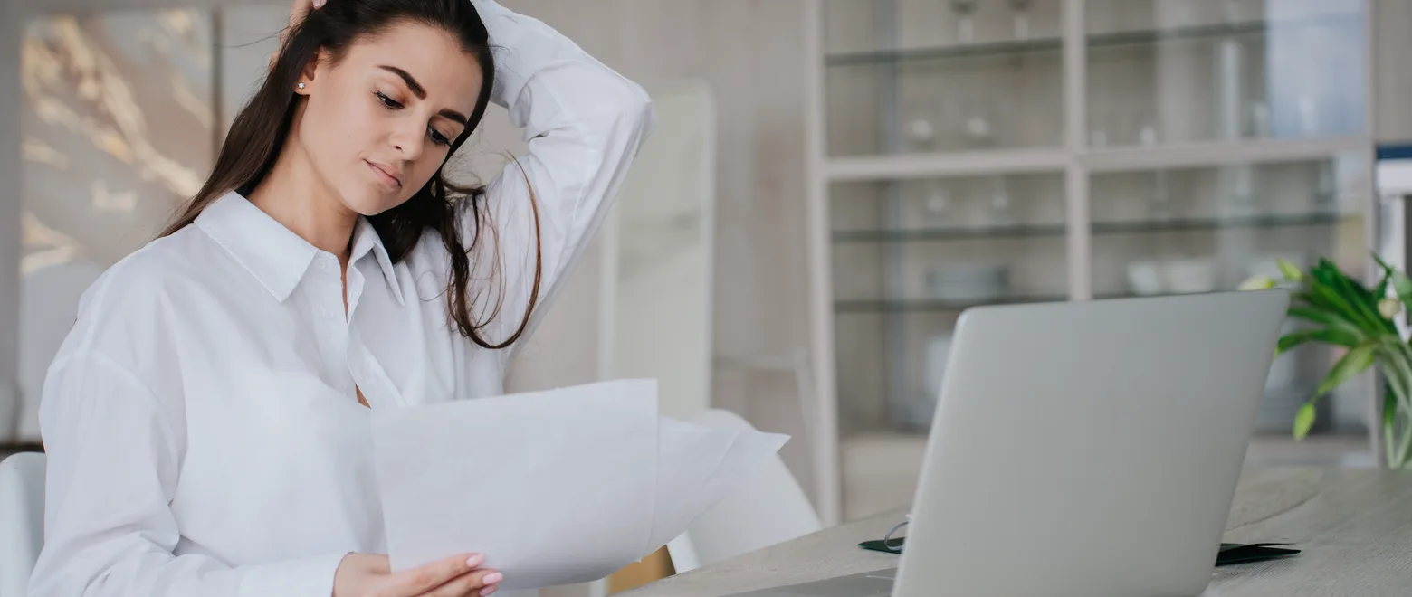 An adult reviews a coverage termination letter and health-plan documents at a home desk