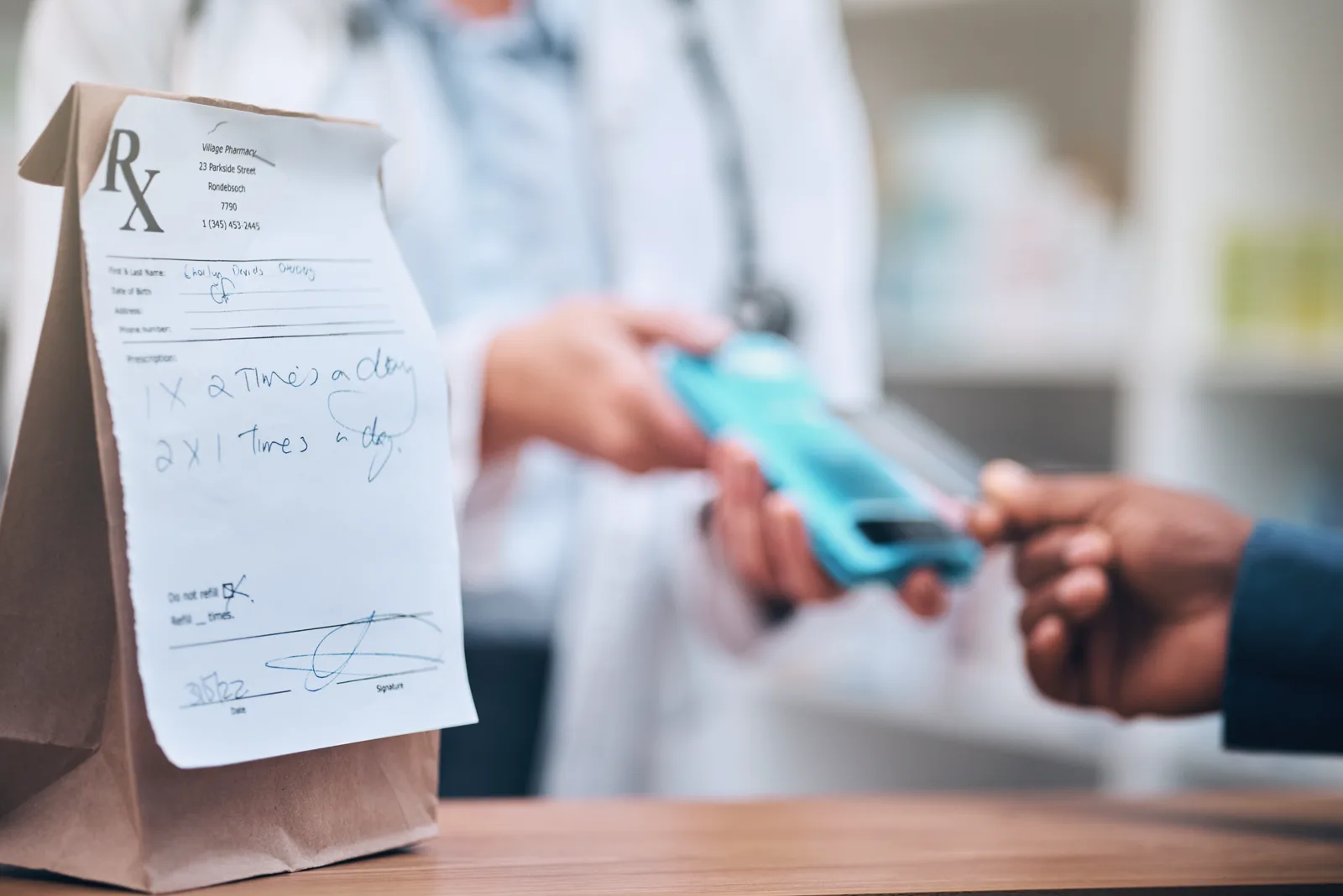 A pharmacy customer paying at the counter beside a prescription bag